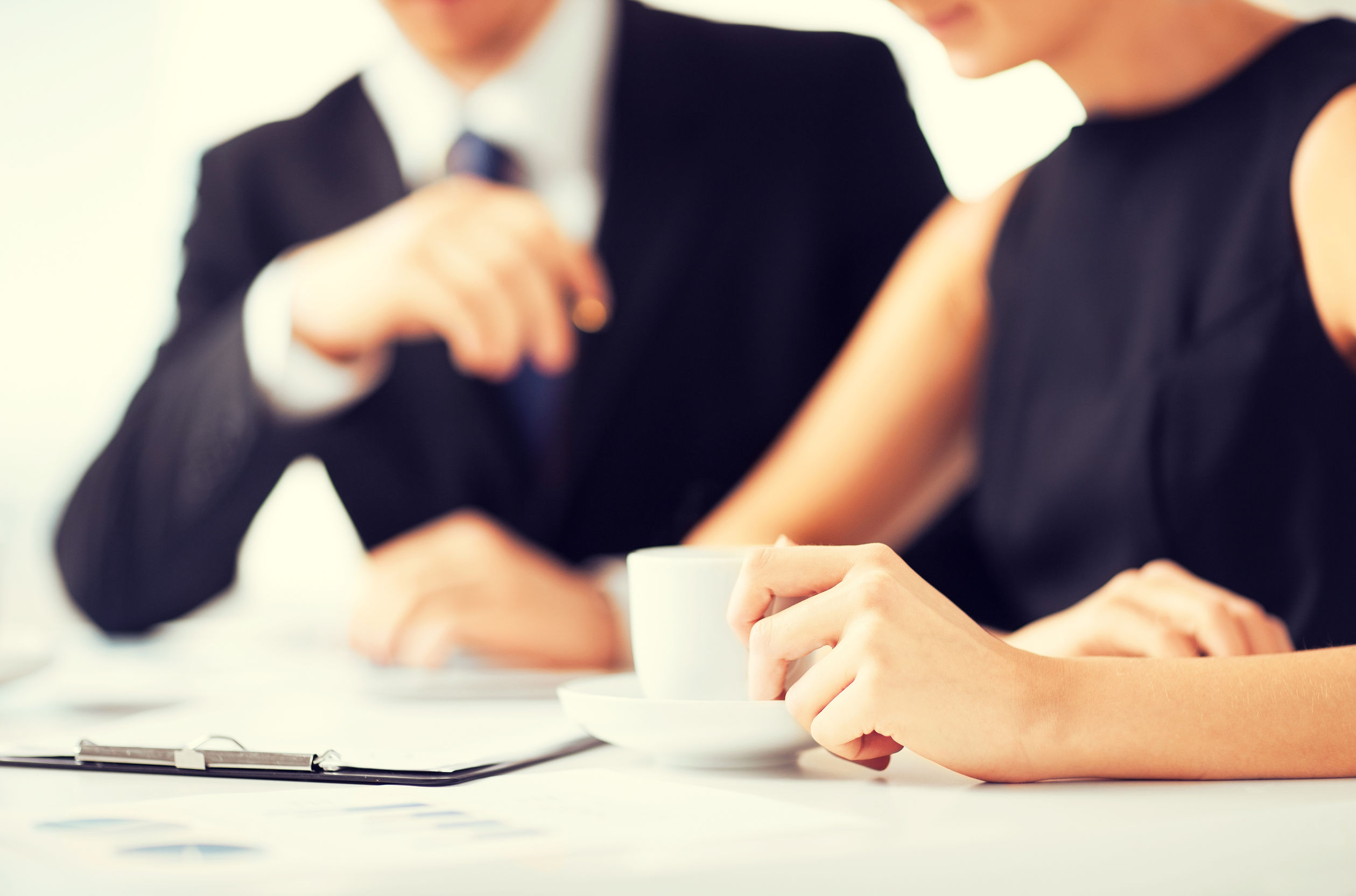 Business professionals having coffee break with documents and clipboard in the foreground.